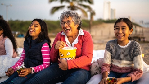 Grandmother with grandchildren watching a movie at the outdoors cinema