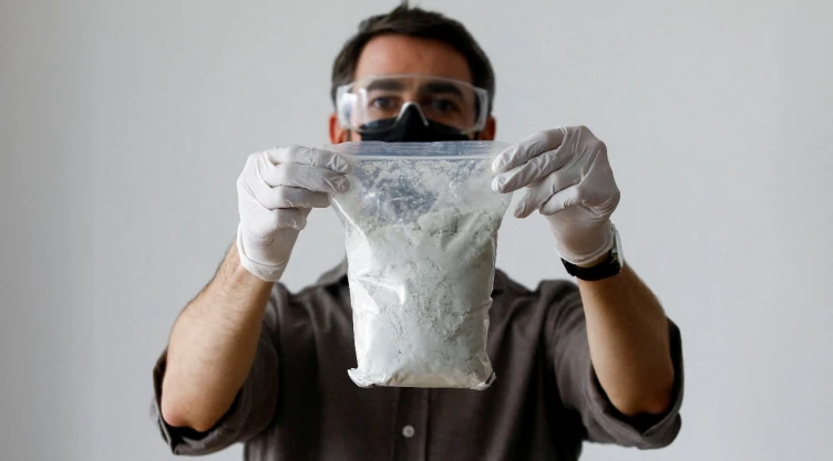 Hombre sostiene bolsa transparente con precursores de fentanilo.
