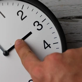 Mano ajusta manecillas de un reloj