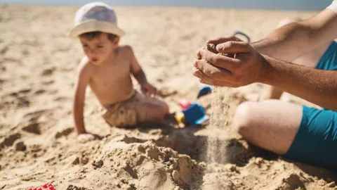 Un hombre juega con un niño en una playa.