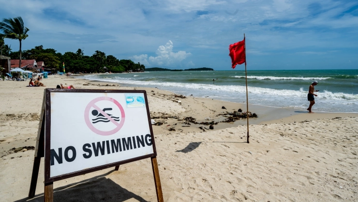 La costa de una playa con bandera roja y un cartel que dice “no nadar”