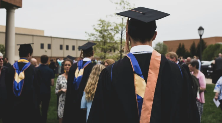 Un estudiante en su gradación de la universidad con la toga, la esclavina, el birrete y la borla
