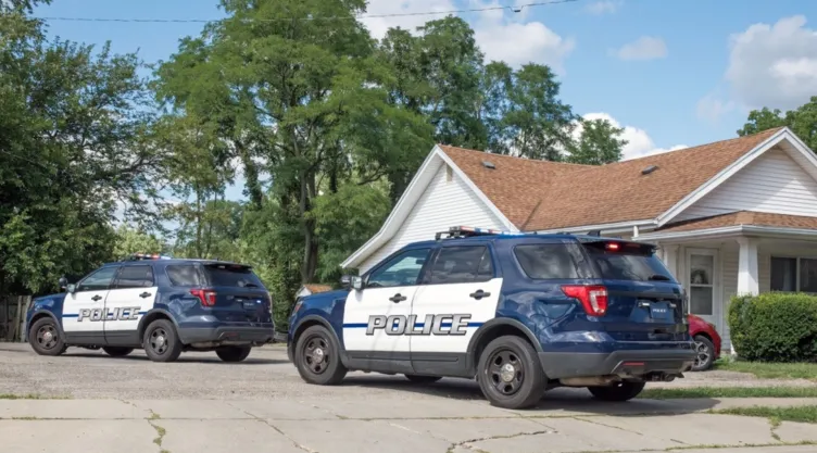 Dos autos de policía frente a una casa.