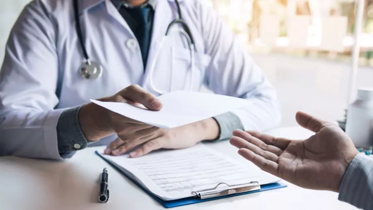 Un doctor entrega una factura a un paciente.