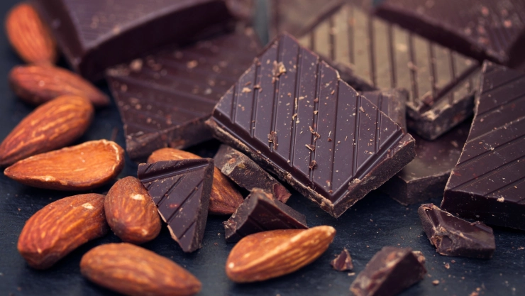 un pedazo de choxolate negro junto a almendras