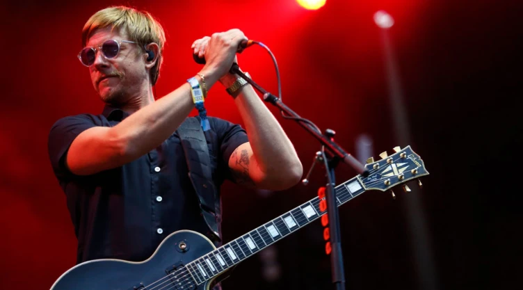 Paul Banks, de la banda Interpol, con un micrófono y una guitarra.