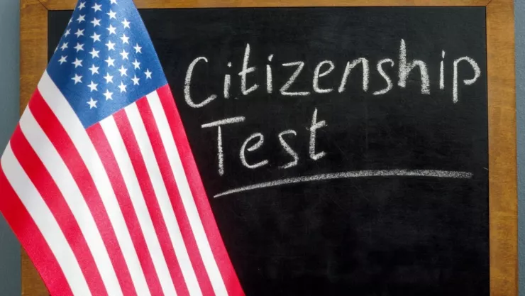 Una pizarra en la que dice “Test de ciudadanía” detrás de una bandera de Estados Unidos.
