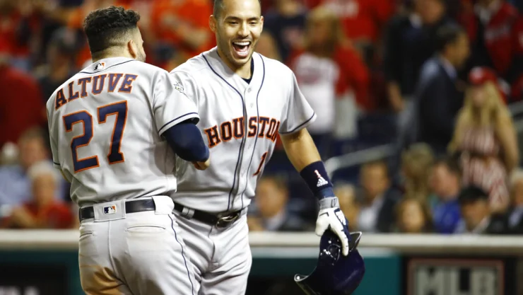 El puertorriqueño Carlos Correa, de los Astros de Houston, festeja con el venezolano José Altuve, tras conectar un jonrón de dos carreras en el quinto juego de la Serie Mundial ante los Nacionales de Washington, el domingo 27 de octubre de 2019. I