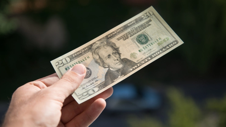 Persona entregando billete de 20 dólares