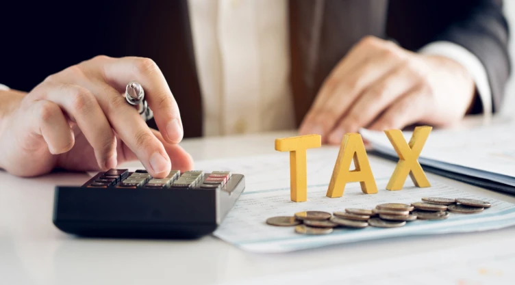 un hombre cuenta su dinero junto a un concepto de impuestos
