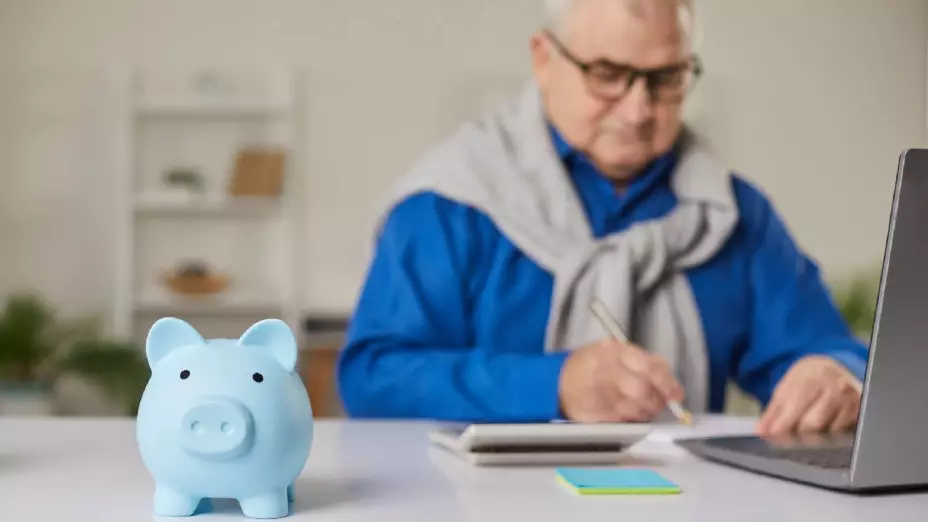 un señor mayor hace sus cuentas frente a una computadora