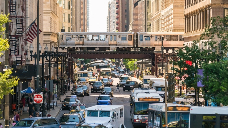 Una calle de Chicago con coches, autobuses y trenes.