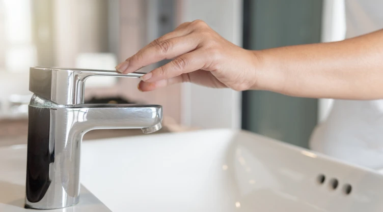 Una personas cierra el grifo de agua.