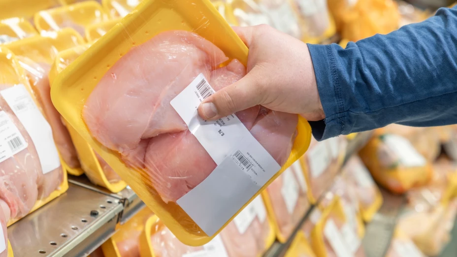 Una persona adquiere una bandeja de pollo en el supermercado.
