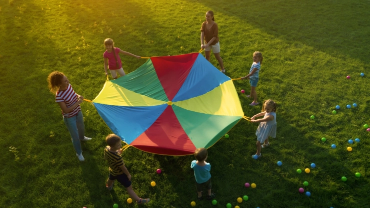 Un grupo de niños y una maestra juegan en un parque.