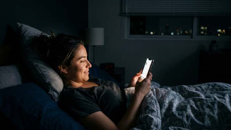 Mujer acostada viendo el celular antes de irse a dormir