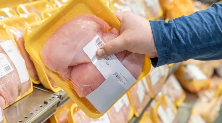 Una persona adquiere una bandeja de pollo en el supermercado.