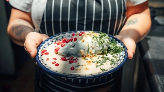 Chef sosteniendo un plato de chile en nogada.