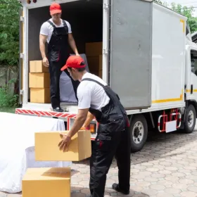Dos personas suben cajas a un camión de mudanza.