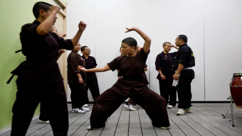 Monjas budistas en túnicas rojas realizando movimientos de Kung Fu en un entorno montañoso.