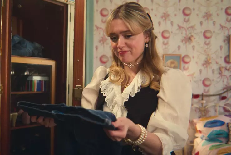 Aimee Lou Wood mirando unos pantalones en su papel de Sex Education, serie de Netflix