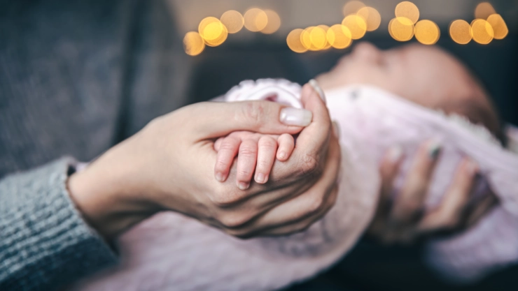 Close-up of a pen of a newborn baby girl in mom’s hand.