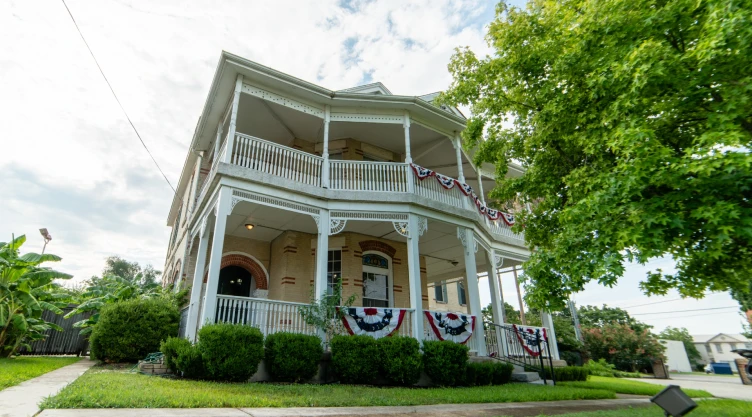 Una casa de dos plantas en un pueblo de Texas, con un parque verde de entrada prolijo y plantas en su alrededor