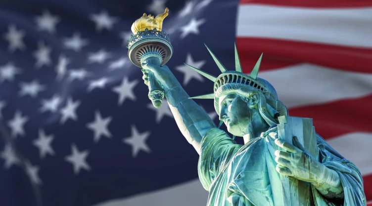 La Estatua de la Libertad junto a la bandera de Estados Unidos