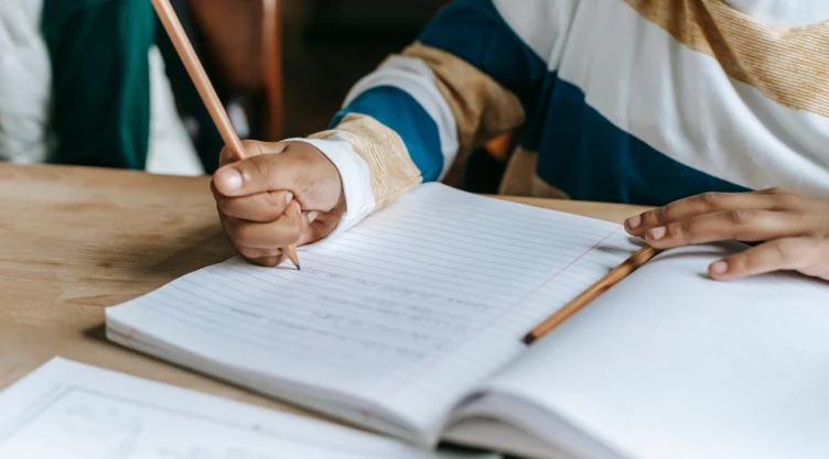 Alumno con cuaderno y lápiz en mano.