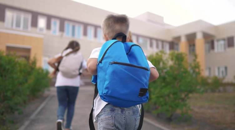 Dos niños corren para entrar a la escuela.