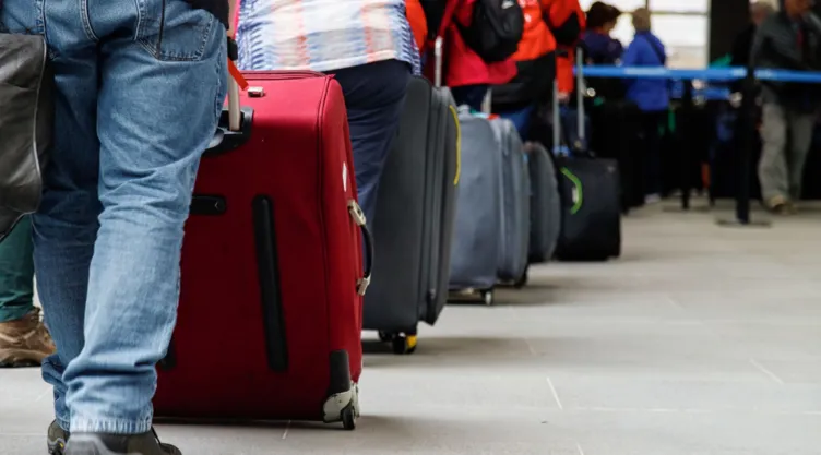 Unos viajeros hacen fila en un aeropuerto.