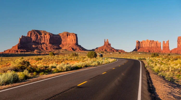 Una carretera desierta en Arizona con el fondo de montañas rocosas de color rojizo