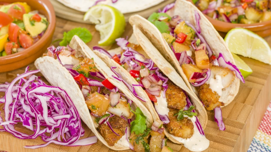 Tres tacos servidos en la mesa con sus respectivos ingredientes, listos para comer