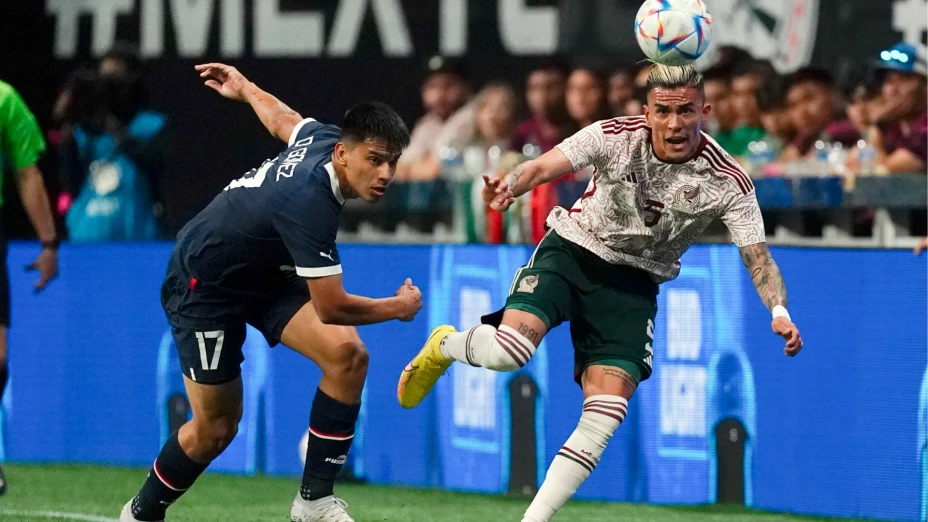 Disputa de un balón en juego México vs Paraguay.