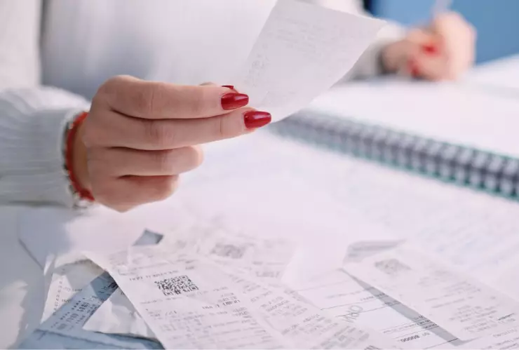 mujer con varios recibos para facturar o registrándolos en un cuaderno