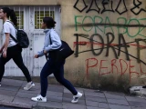 Mujeres pasan junto a grafitis que dicen “Fuera Bozo”, “Fuera PT” y “Perdiste” un día después de que el senador brasileño de derecha Flavio Bolsonaro y el presidente de izquierda Luiz Inácio Lula da Silva avanzaran a una segunda vuelta tras la primera ronda de votación, en Porto Alegre, Brasil , 5 de octubre de 2026.