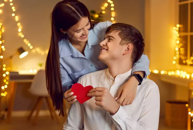 Una pareja sostiene un corazón rojo.