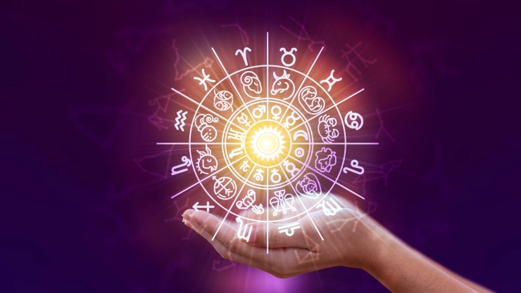 Una mujer sostiene la imagen de los signos del Zodiaco