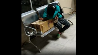 Una mujer indígena sentada en las bancas del Hospital Macas en Ecuador abrazando la caja de cartón en la que le entregaron el cuerpo de su hija