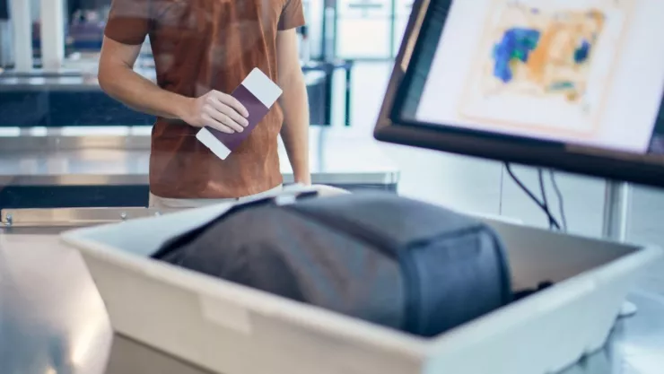 Un hombre pasa una maleta de mano por un scanner.