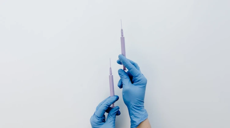 Jeringas sostenidas por unas manos con guantes de médico.