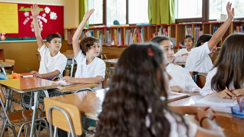 niños en la escuela levantando la mano para participar