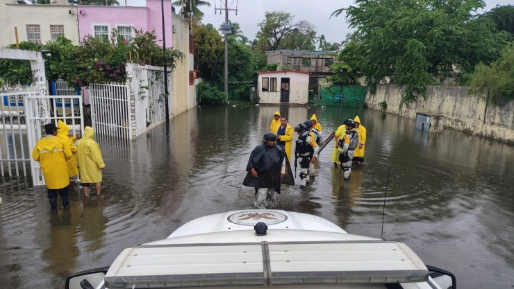 Patrulla de la Guardia Nacional sobre una calle completamente inundada en Guerrero por el paso del huracán “Erick”, al fondo se ven elementos caminando entre el agua con overoles amarillos.