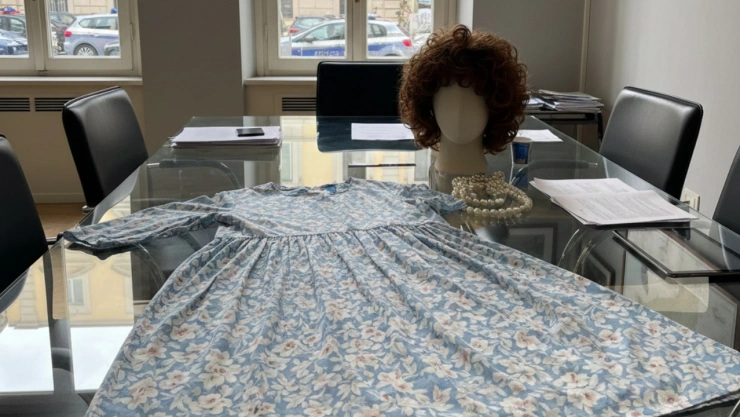 Imagen generada con Gemini AI que mustra un vestido floral, una peluca castaña sobre una mesa transparente dentro de una oficina.