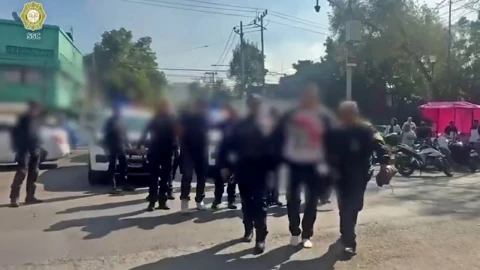 Personas detenidas son escoltadas por policías de la SSC durante un operativo contra extorsión en la alcaldía Cuauhtémoc.