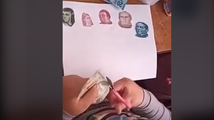 Niña recorta billetes para ilustrar su tarea