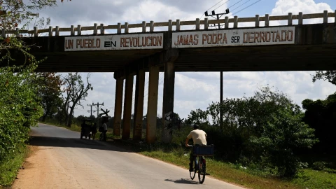 Un hombre anda en bicicleta por la calle junto a una valla publicitaria que dice: “Un pueblo en revolución jamás podrá ser vencido ", en San Antonio de los Baños, Cuba, el 3 de marzo de 2026.