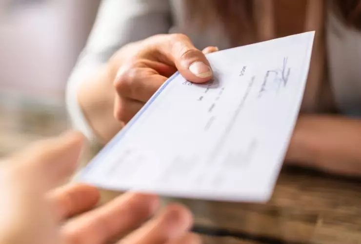 Una persona entrega un cheque a otra,
