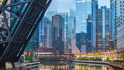Imagen de la ciudad de Chicago tomada desde un puente, donde se aprecia el río y los edificios al atardecer