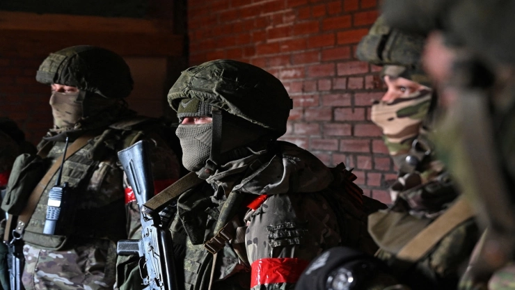 Soldados con uniforme militar en una zona de combate, con armas y equipo militar.